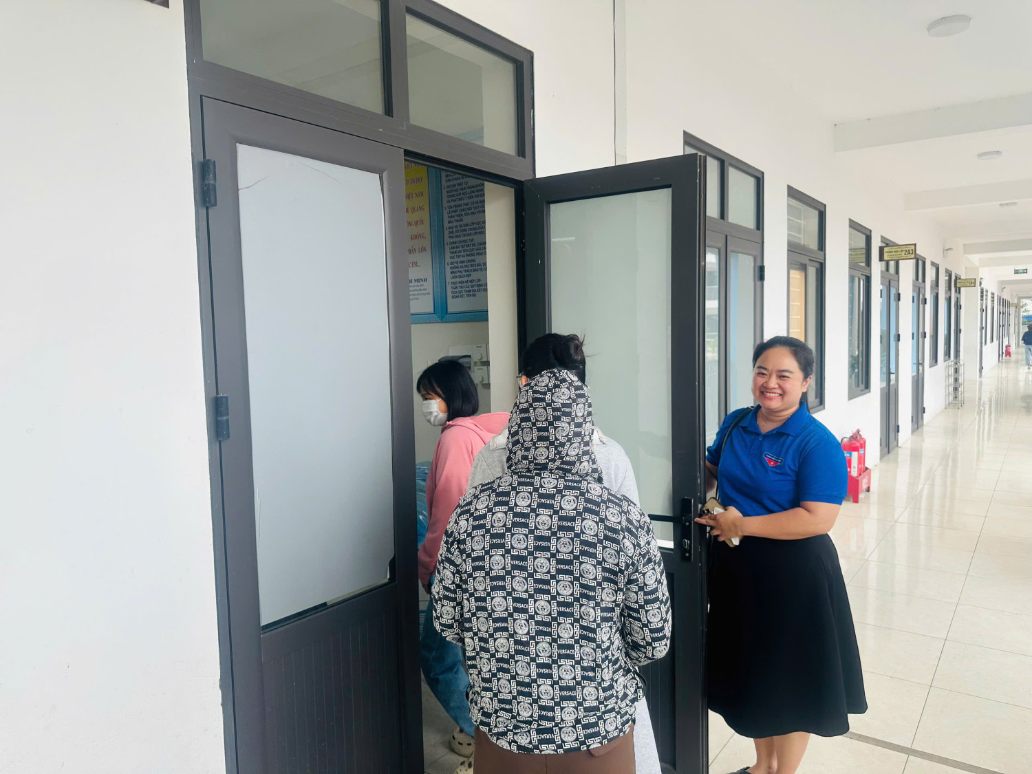 Đoàn viên thanh niên nhà trường hướng dẫn người nhà thí sinh vào phòng học nghỉ chờ